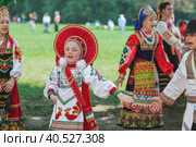 Russian folk traditions. Folk festivals. Children in beautiful Russian traditional outfits sing songs, dance and lead a round dance in Tsaritsyno Park. National Russian clothes. Sundresses and kokoshniks. (2023 год). Редакционное фото, фотограф Photojuli / Фотобанк Лори