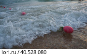 Buoys on a rope near sea water. The buoys are pink restraints to alert people to the depth of the water. Rescue of the drowning. Delimiting a place on a sandy beach between hotels. Wave with bubbles. Стоковое фото, фотограф Юлия Петровская / Фотобанк Лори