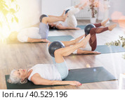 People lying on karemat, pulled bent legs to themselves and clamped soft-ball in knee. Стоковое фото, фотограф Яков Филимонов / Фотобанк Лори