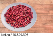 Red shelled raw peanut nuts on a vintage wooden table. Стоковое фото, фотограф Iva Noel / Фотобанк Лори
