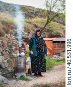 People of Caucasus. Old Dagestani (avar) lady. The hospitable hostess of an authentic cafe poses by the hearth where delicious tea is prepared. (2021 год). Редакционное фото, фотограф Саблин Станислав / Фотобанк Лори