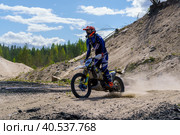Мотоциклист в экипировке на эндуро мотоцикле на соревнованиях в Карелии, песчаный карьер близ поселка Эссойла (2023 год). Редакционное фото, фотограф Sergei Gorin / Фотобанк Лори