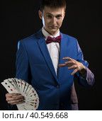 Handsome illusionist showing tricks in the dark. Стоковое фото, фотограф Гурьянов Андрей / Фотобанк Лори