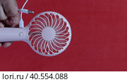 A man connects a charger cable to a portable fan. Then disconnect the cable from the device. On a coral background. Close-up. Стоковое видео, видеограф Vadzim Yakubovich / Фотобанк Лори