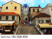 Herceg Novi, Montenegro, old town, Sat-kula tower, Sahat-kula, Tora, chapel tower or Clock tower 08.09.22 Tourists walk along the aisle under the city clock. Sunset, golden hour, summer evening. (2022 год). Редакционное фото, фотограф Юлия Петровская / Фотобанк Лори