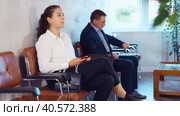 Serious-minded female candidate siting on chair and waiting for job interview in hallway. Стоковое видео, видеограф Яков Филимонов / Фотобанк Лори