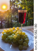 Glass of red wine and a bunch of white grapes at sunset. Стоковое фото, фотограф Iva Noel / Фотобанк Лори