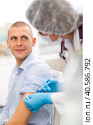 Doctor in a protective mask injects a vaccine to a man with syringe. Стоковое фото, фотограф Яков Филимонов / Фотобанк Лори