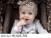 Funny pensive baby with blue eyes sitting in stroller, sad looking at camera. Adorable bored cute child infant with fingers in mouth in pram. Concept of infancy, childhood emotion. Copy ad text space. Стоковое фото, фотограф Aleksandr Golubev / Фотобанк Лори