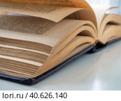 An old thick book is open and lies on the table. The book is located diagonally. Pages turned yellow from old age. Стоковое фото, фотограф Бузмакова Светлана / Фотобанк Лори