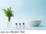 A bottle of essential oil with fresh juniper branches. Homeopathic globules and glass bottles near a white plate. Стоковое фото, фотограф Tatiana Syrtseva / Фотобанк Лори