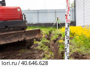 Инженер с нивелиром просматривает уровень земли в траншее, вырытой экскаватором. Стоковое фото, фотограф Кекяляйнен Андрей / Фотобанк Лори