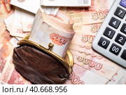 Пачка рублевых пятитысячных купюр лежит в старом кошельке на фоне денежных купюр рублей. Стоковое фото, фотограф Николай Винокуров / Фотобанк Лори