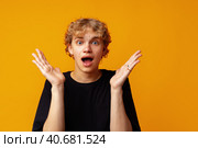 Young man over yellow background with surprise facial expression. Стоковое фото, фотограф Сергей Толмачёв / Фотобанк Лори