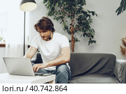 Young man businessman with headset working on laptop from home. Стоковое фото, фотограф Сергей Толмачёв / Фотобанк Лори