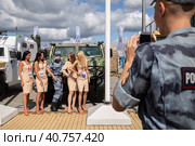 Международный военно-технический форум "Армия-2021". На открытой выставочной площадке перед военной техникой четыре нарядные девушки и росгвардеец фотографируются на память. Редакционное фото, фотограф Наталья Николаева / Фотобанк Лори