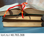 Old thick books lie in a pile on the table. The top book is open. Bookmark at the top of open pages. The concept of scientific work, reading the bible, monographs, gaining knowledge. Стоковое фото, фотограф Бузмакова Светлана / Фотобанк Лори
