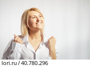 Portrait of a pretty blonde smiling woman posing on a white background. Happy girl model in white shirt in studio. Lady winner is joyfull. Copy space. Стоковое фото, фотограф Кривошеина Елена Леонидовна / Фотобанк Лори