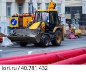 Excavator - loader rides on the construction site. In the foreground are long red pipes. Visible construction machinery and equipment. Стоковое фото, фотограф Бузмакова Светлана / Фотобанк Лори