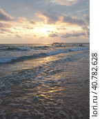 Wave and sunset over sea. Beautiful sunset. Foamy waves roll over the sandy shore. Vityazevo, Anapa, Black Sea. Tourist mecca, health resort. Evening sky. The rays reflect off the water. Стоковое фото, фотограф Юлия Петровская / Фотобанк Лори