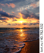 Sunset over sea. Beautiful sunset. Foamy waves roll over the sandy shore. Vityazevo, Anapa, Black Sea. Tourist mecca, health resort. Colorful clouds in the evening sky. The rays reflect off the water. Стоковое фото, фотограф Юлия Петровская / Фотобанк Лори