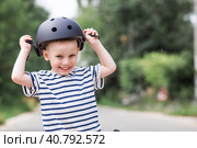A cheerful little boy rides a running bike in a helmet outdoors. A happy child is engaged in an active sport. Protection. Life insurance and child safety. Стоковое фото, фотограф Photojuli / Фотобанк Лори