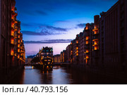 The Warehouse District - Speicherstadt in twilight. Tourism landmark of Hamburg. View of Wandrahmsfleet in light of lantern lamp. Port of Hamburg within the HafenCity quarter (2018 год). Стоковое фото, фотограф Igor Tichonow / Фотобанк Лори
