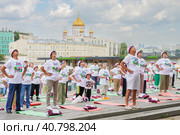 Московские пенсионеры делают гимнастику в парке Музеон на фоне храма Христа Спасителя, голубого неба и красивых кучевых облаков. Все одеты в фирменные московские футболки и головные уборы, подаренные правительством Москвы. (2023 год). Редакционное фото, фотограф Сергей Никифоров-Гордеев / Фотобанк Лори
