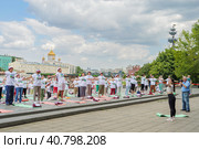 Пенсионеры, участники спортивного праздника программы "Московское долголетие», в фирменных московских футболках и шапочках, стоя на разноцветных гимнастических ковриках, выполняют гимнастику под руководством опытного тренера в парке Музеон в Москве на фоне храма Христа Спасителя, голубого неба и кучевых облаков (2023 год). Редакционное фото, фотограф Сергей Никифоров-Гордеев / Фотобанк Лори