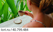 Woman smells and tries to drink hot coffee kopi luwak enjoying green tropical garden nature. Close-up rear view of lonely travel girl in Bali Island Nusa Penida Indonesia. Стоковое фото, фотограф Ольга Сухарева / Фотобанк Лори
