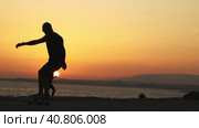 Silhouette of a man skating on a longboard at bright orange sunset by the ocean. Стоковое видео, видеограф Константин Шишкин / Фотобанк Лори