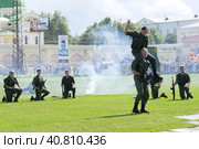 2 августа на празднике дня ВДВ на показательных выступлениях спецназа.  Один десантник сидит на плечах другого и замахивается для удара ножом. Другие десантники с автоматами в руках наблюдают. Сзади видны задымлённые трибуны, наблюдающие зрители и фрагмент православного Храма. (2015 год). Редакционное фото, фотограф Сергей Никифоров-Гордеев / Фотобанк Лори