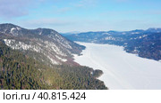 Горный Алтай зимой: лес на берегу Телецкого озера. Вид с воздуха. Altai mountains in winter: forest on the shores of Teletskoye Lake. Aerial view. Стоковое видео, видеограф Евгений Романов / Фотобанк Лори