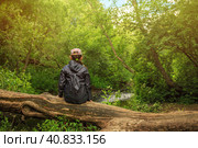 The girl sits on a fallen tree and admire the beautiful forest river. Outdoor activities and hiking in the woods with children. Family travel and adventures in the summer holidays. Стоковое фото, фотограф Андрей Степанов / Фотобанк Лори