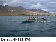 Youth team of rowers on a traditional skin boat (bajdara) during the competition. Regatta on traditional Chukchi and Eskimo boats. Tkachen Bay, Novoye Chaplino, Chukotka, Russia. Редакционное фото, фотограф Андрей Степанов / Фотобанк Лори