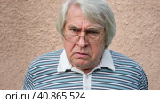 Closeup portrait of an old man, grandfather looking very unhappy, mad and angry isolated on concrete wall background. Senior man facial expression, Menacing Man with gray hair. Negative elderly person. Стоковое видео, видеограф Марина Демидюк / Фотобанк Лори