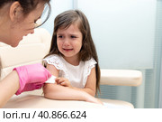 A doctor injects a vaccine to a little girl. The girl is afraid and crying. Стоковое фото, фотограф Ирина Михайличенко / Фотобанк Лори