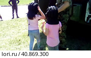 Sremska Mitrovica Serbia 18 May 2019 Demonstrations of tank troops. Two soldiers put tank helmets on the girls heads and prepare them to board a tank or armored carrier. Children near the tank. Редакционное видео, видеограф Юлия Петровская / Фотобанк Лори