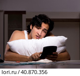 Young man calculating expences night at home. Стоковое фото, фотограф Elnur / Фотобанк Лори