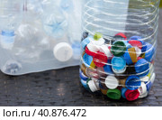 A container made of plastic bottles and plastic lids. Garbage collection around the world. Clean the planet of plastic garbage. Ecology. Sorting garbage. Стоковое фото, фотограф Photojuli / Фотобанк Лори
