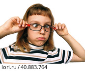 Cute 7 year old Caucasian girl looks into glasses. Eyes in a bunch. Ophthalmic problems in children. Myopia, exophoria and astigmatism. Selection of glasses. Isolate white background. Back to school. Стоковое фото, фотограф Юлия Петровская / Фотобанк Лори