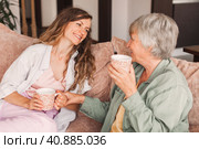 Happy adult daughter and senior mother having fun enjoying talk sit on sofa at home. Стоковое фото, фотограф Гладских Татьяна / Фотобанк Лори