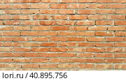 Orange brick wall frontally. Ceramic brickwork or fence. Neatly and evenly laid brick. The light wall of the building, gray cement in the cracks. Sunny evening lighting. Стоковое фото, фотограф Юлия Петровская / Фотобанк Лори