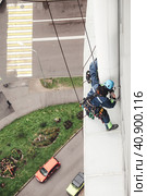 Industry mountaineer workers hangs over residential house facade, access high rise work. Two laborers in uniform and helmets working on wall building. Industrial urban work concept. Copy ad text space. Стоковое фото, фотограф Aleksandr Golubev / Фотобанк Лори