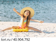 Happy cute smiling little girl in straw hat has fun on the sand on a beach in a swimsuit. Summer concept. Стоковое фото, фотограф Ирина Михайличенко / Фотобанк Лори