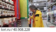Buyer selects paint and plaster in the store (2018 год). Редакционное фото, фотограф Анна Кривицкая / Фотобанк Лори