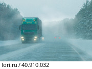 Semi-trailer truck at the interurban road during a heavy blizzard. Cars and truck drive on the road in a snow storm in the evening. Стоковое фото, фотограф Трегубов Николай / Фотобанк Лори