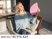 Exhausted middle aged woman using paper waver, suffering from hot summer. Стоковое фото, фотограф Гладских Татьяна / Фотобанк Лори