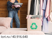 Happy middle aged woman holding cardboard recycling box with clothes. Стоковое фото, фотограф Гладских Татьяна / Фотобанк Лори