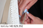 A woman applies a strap and accessories to a knitted bag. Close-up.. Стоковое видео, видеограф Vadzim Yakubovich / Фотобанк Лори